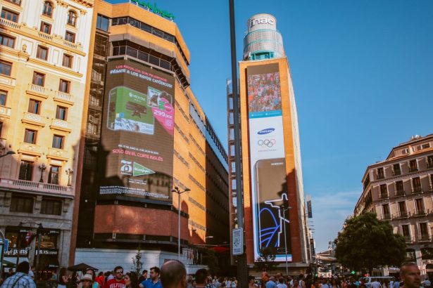 Cena urbana movimentada, com grandes painéis digitais de publicidade e edifícios ao redor.