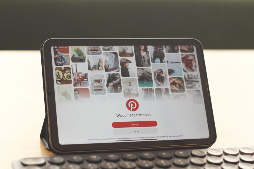 Tablet exibindo a página inicial do Pinterest sobre uma mesa com teclado.
