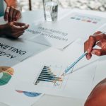 Equipe reunida em um escritório analisa gráficos e documentos durante uma discussão sobre estratégia de marketing.
