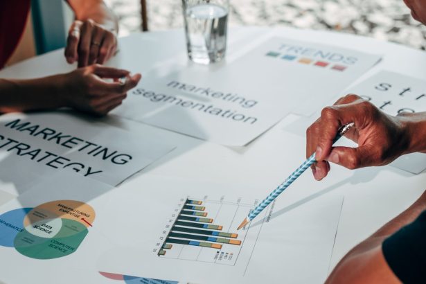 Equipe reunida em um escritório analisa gráficos e documentos durante uma discussão sobre estratégia de marketing.