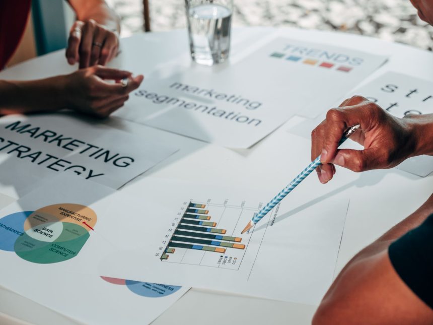 Equipe reunida em um escritório analisa gráficos e documentos durante uma discussão sobre estratégia de marketing.
